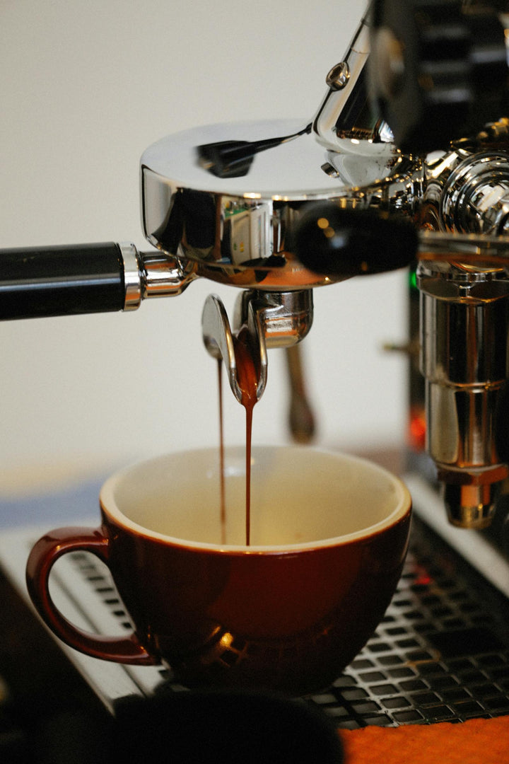 Machine espresso versant du café dans une tasse brune.