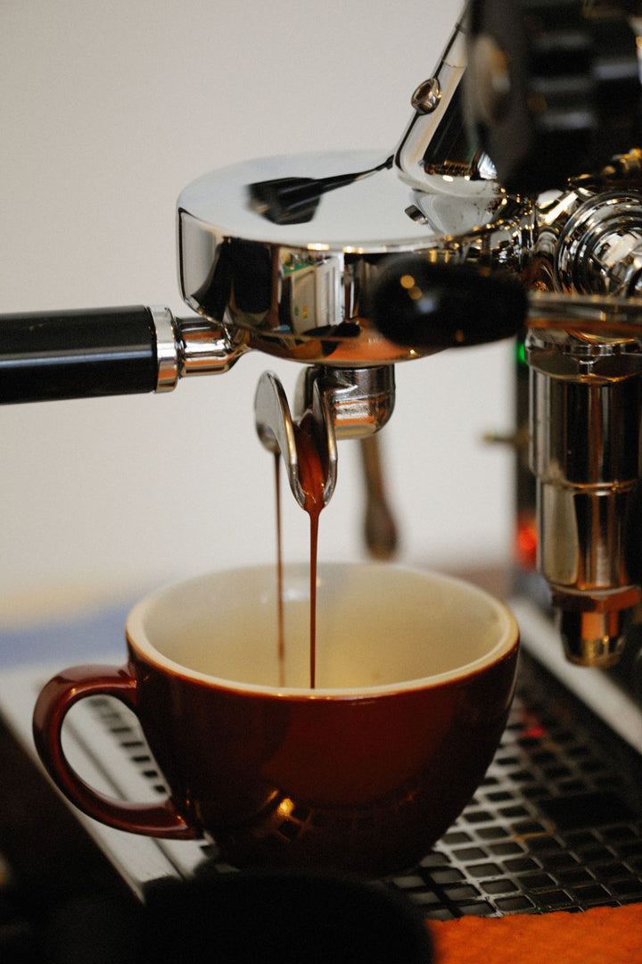 Machine espresso versant du café dans une tasse brune.
