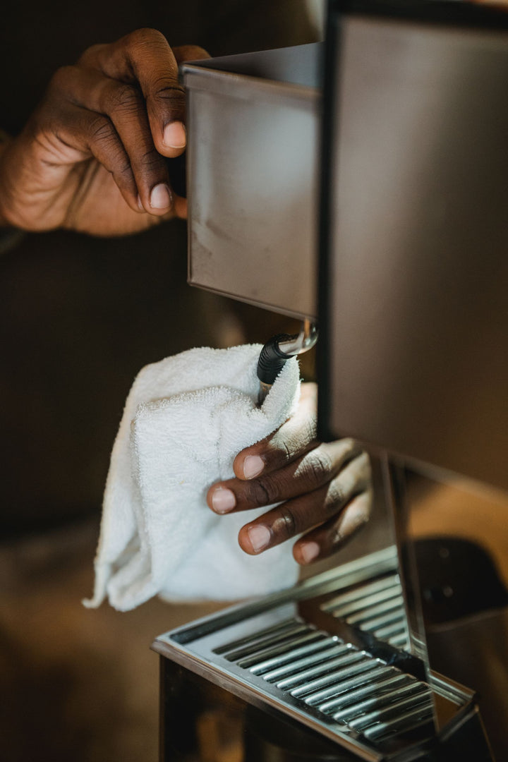 Barista nettoyant une machine à café avec un chiffon.