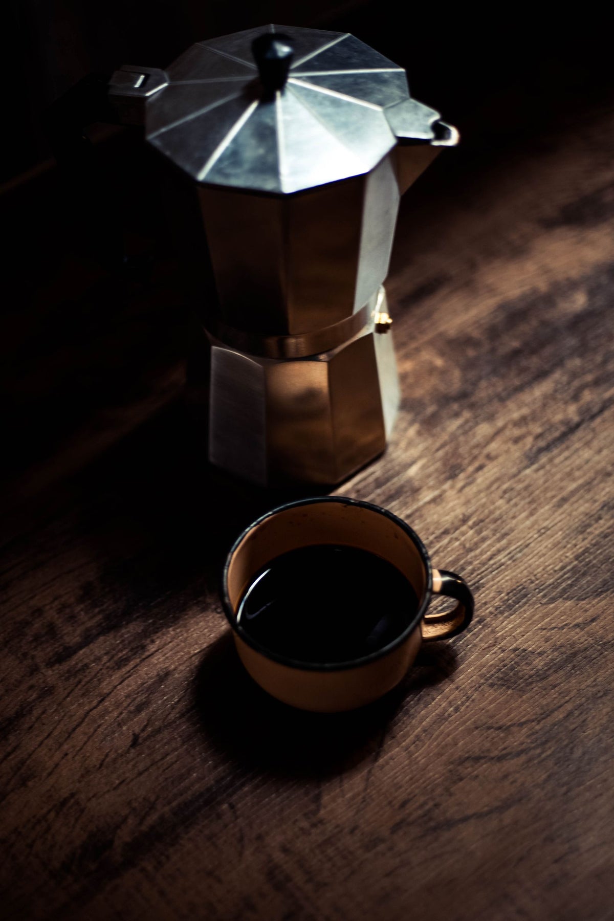 Moka italienne et tasse de café posées sur une table en bois.