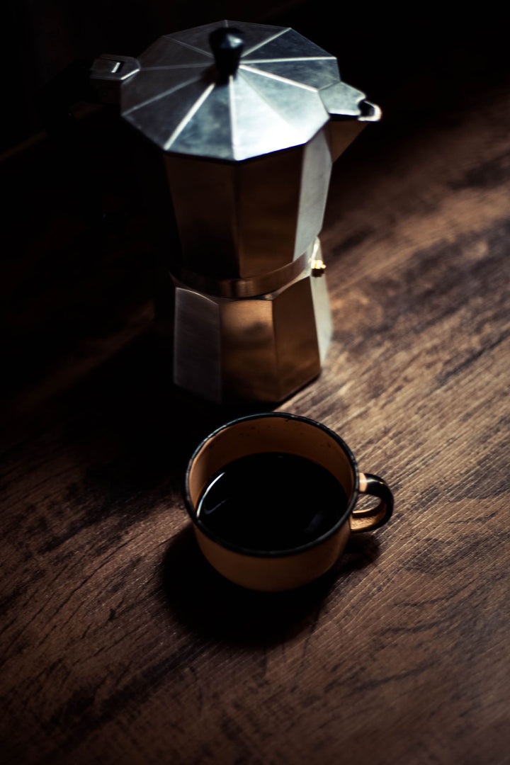 Moka italienne et tasse de café posées sur une table en bois.