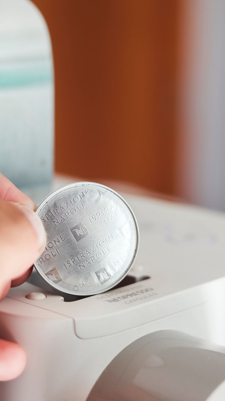 Main insérant une capsule de café dans une machine compacte.