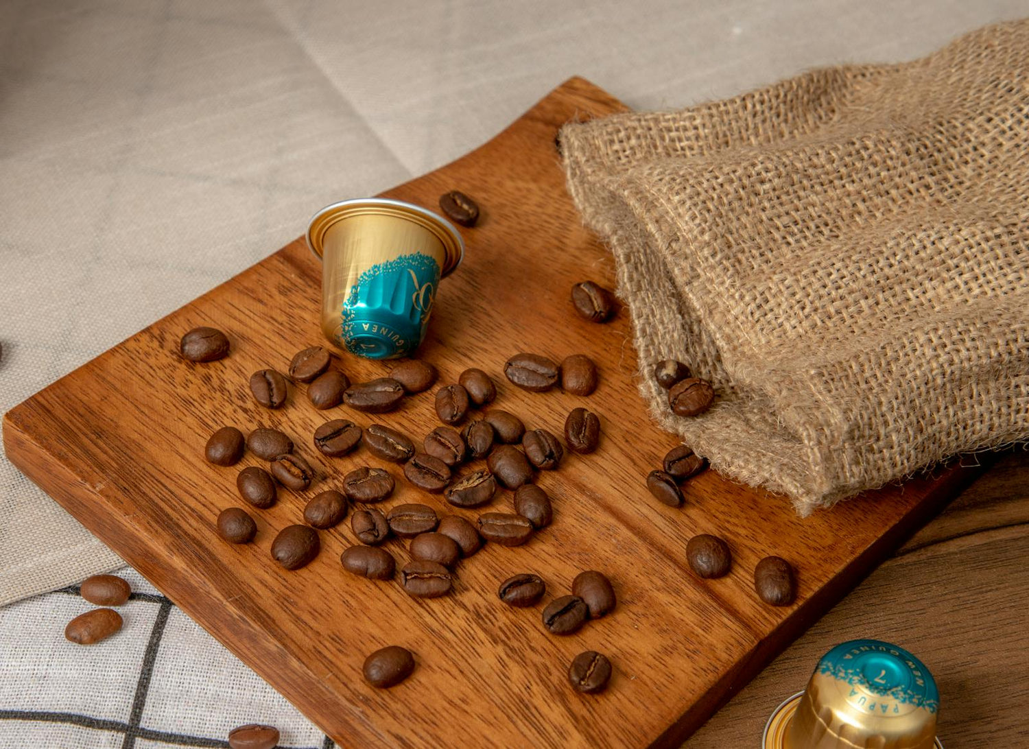 Grains de café et capsules posés sur une planche en bois avec toile de jute.