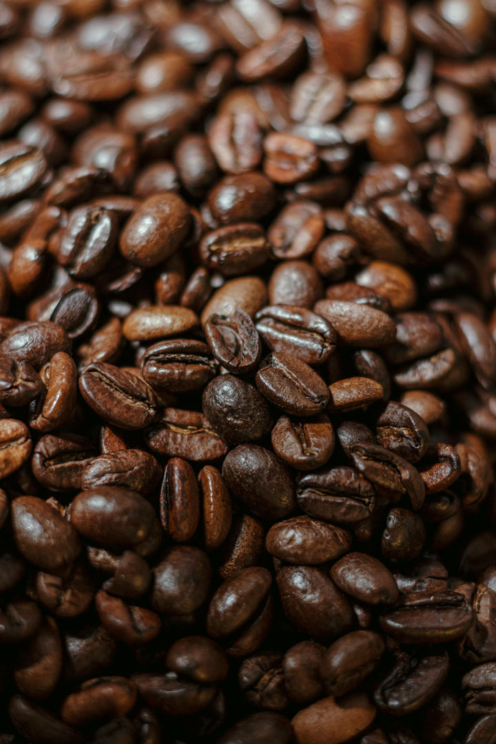Gros plan de grains de café torréfiés foncés.