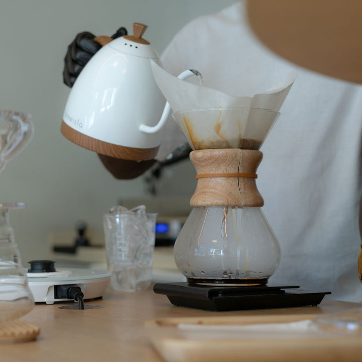 Personne versant de l'eau chaude dans un dripper à café.