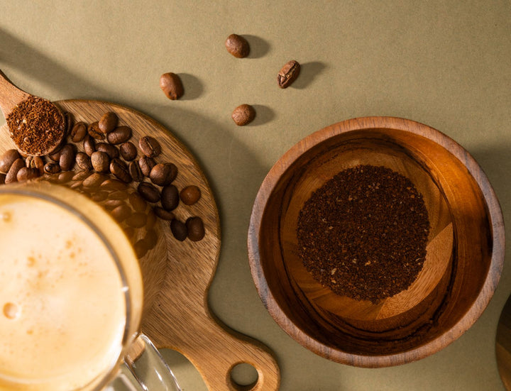 Vue du dessus de grains de café, café moulu et tasse sur une planche en bois.