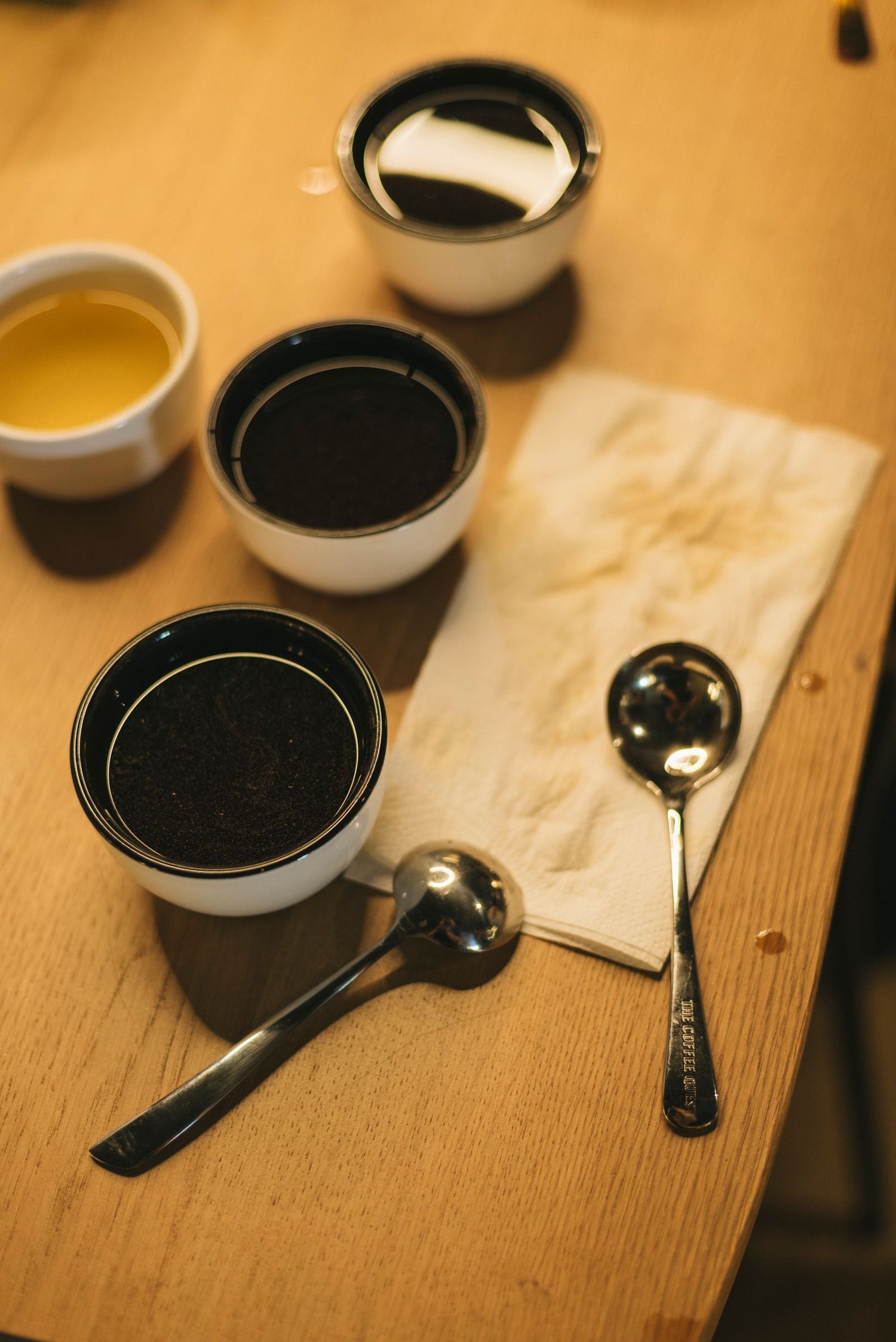 Tasses de dégustation de café avec cuillères sur une table en bois.