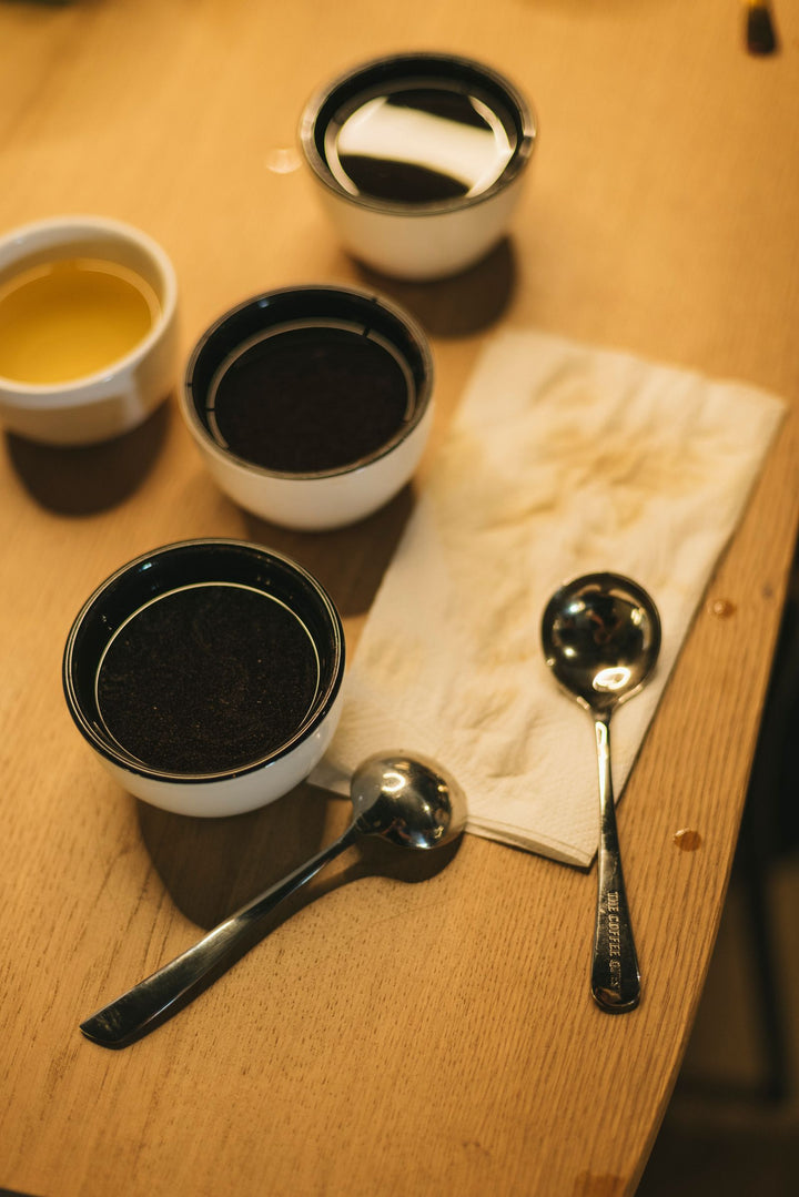 Tasses de dégustation de café avec cuillères sur une table en bois.