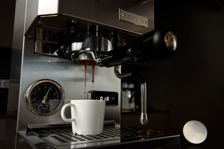 Espresso en cours d'extraction dans une tasse blanche sous une machine.