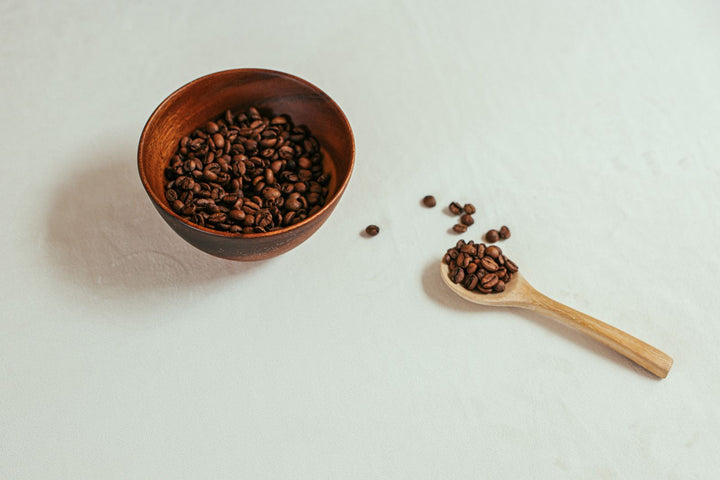 Café en grains dans un bol avec café moulu sur une table claire.